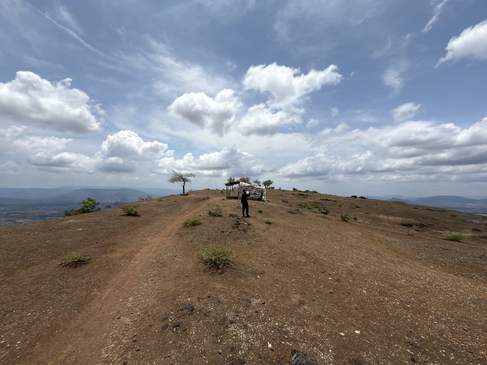 Plateau-top with a small shelter and a solo hiker under a wide sky