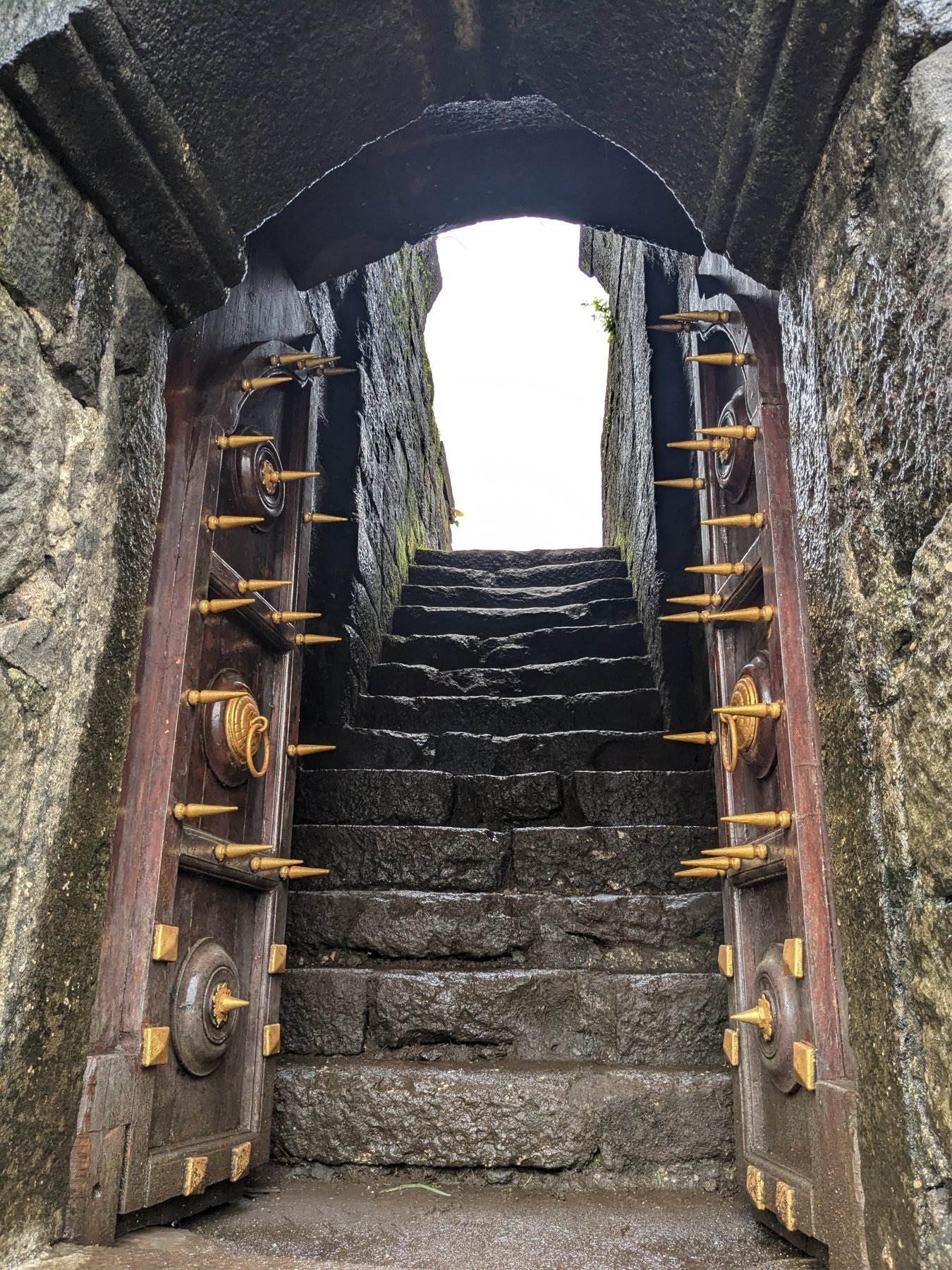 Ancient studded fort gate doors of Karnala leading up stone steps